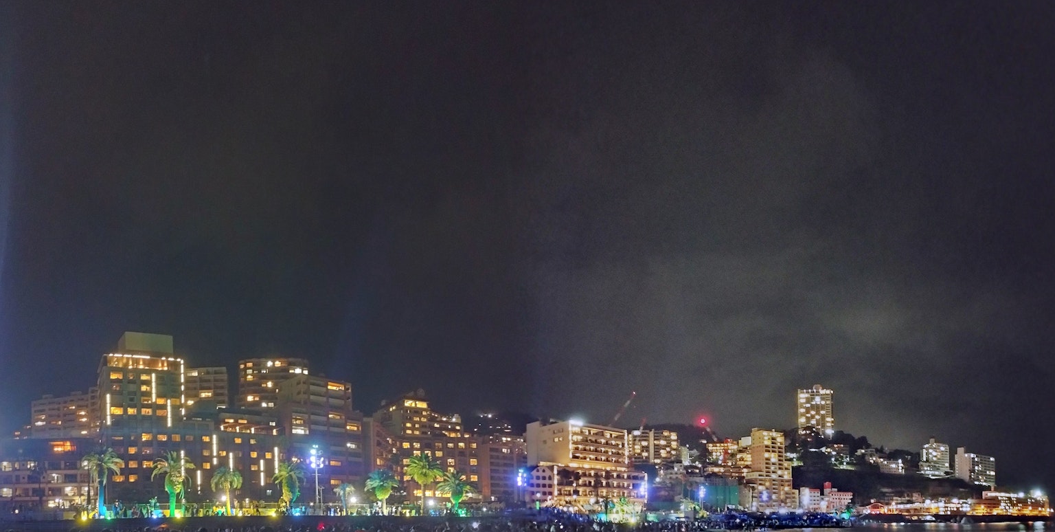 Paesaggio urbano notturno con luci brillanti e cielo nuvoloso