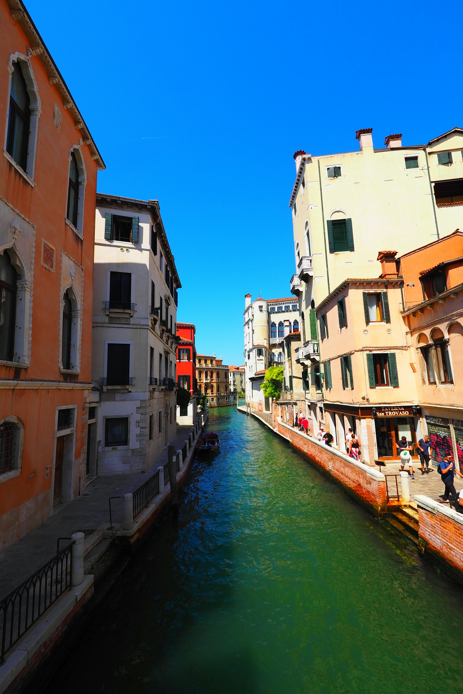 Canal de Venecia con edificios históricos bajo un cielo azul claro