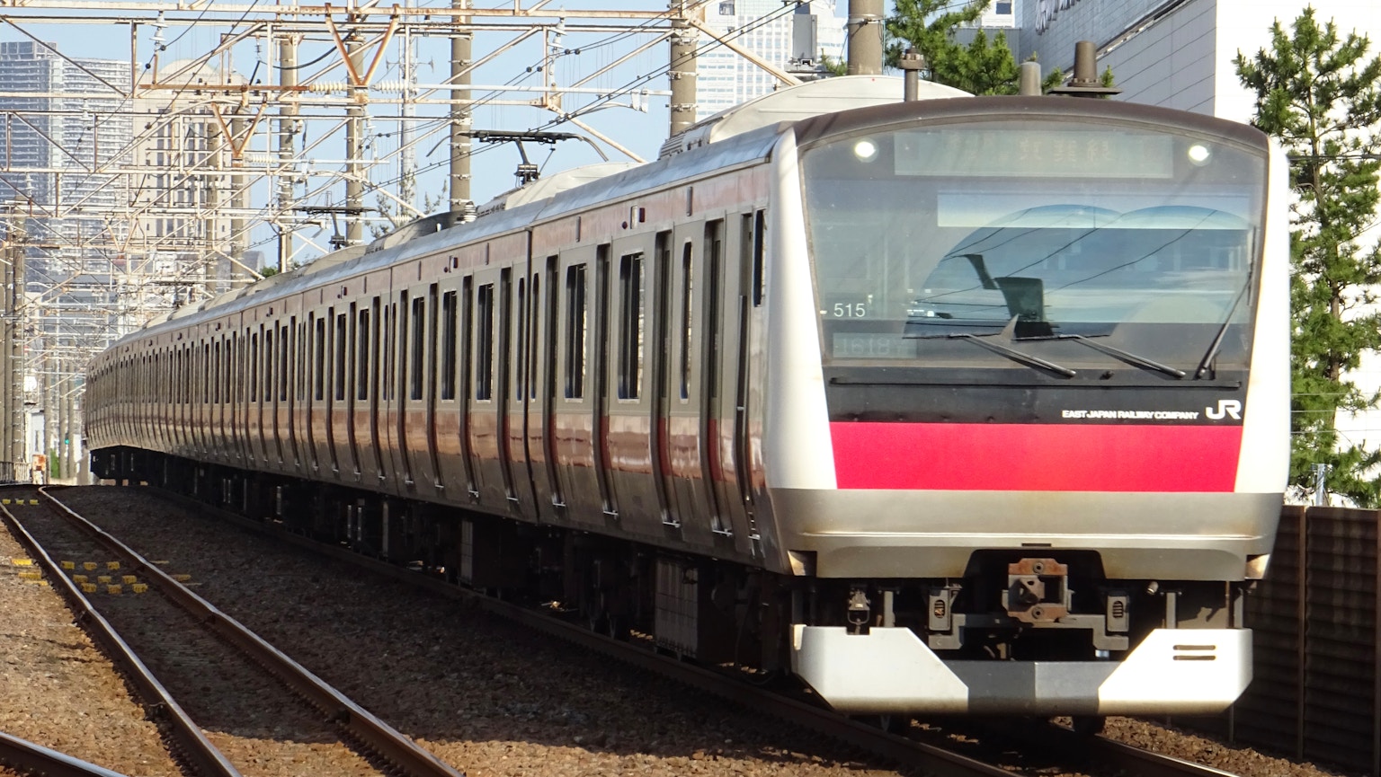 Silver train with red stripe running on tracks