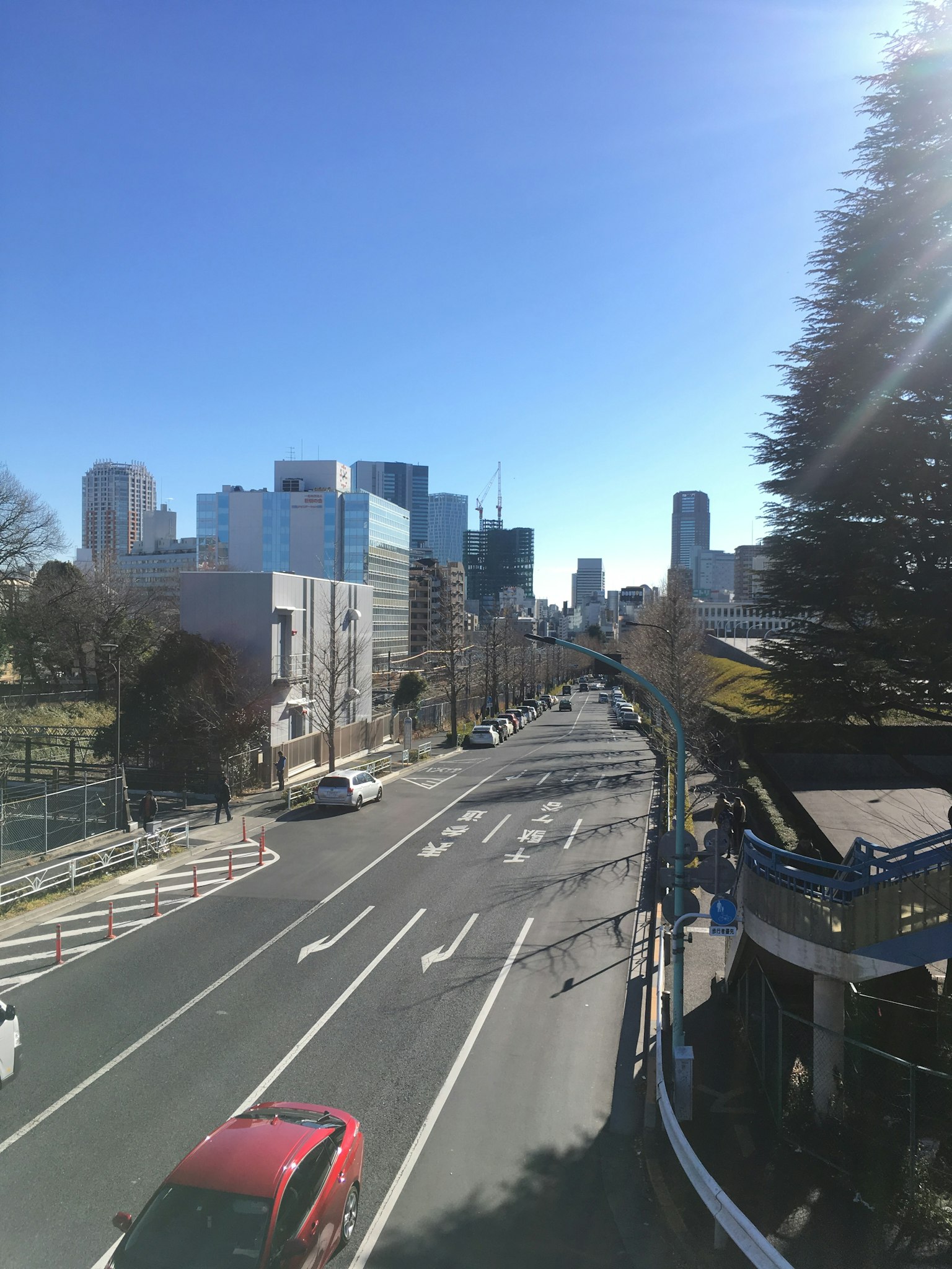 Vue urbaine sous un ciel bleu dégagé avec une route et des voitures ainsi que des bâtiments à proximité