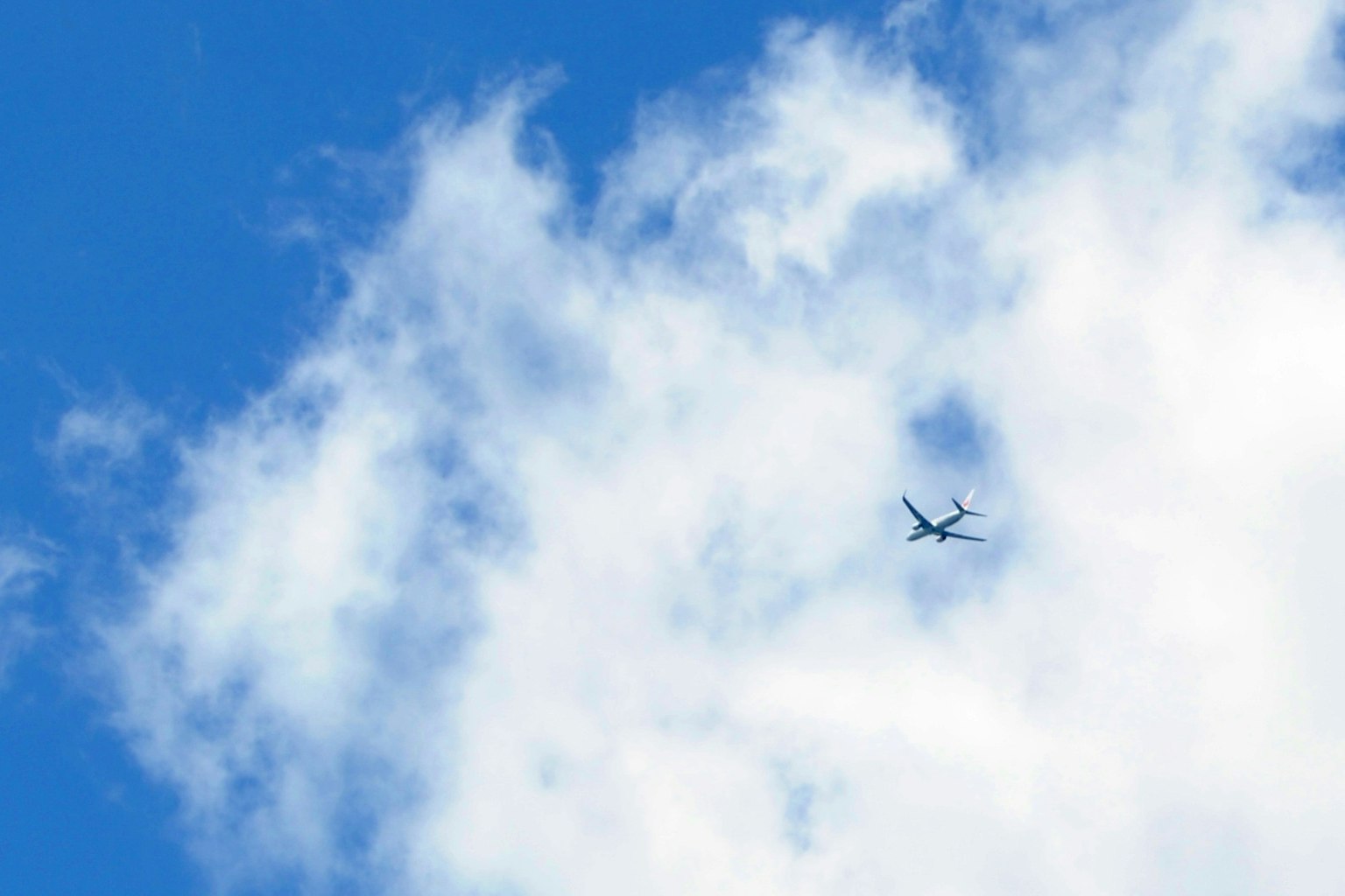 Un avion volant dans un ciel bleu clair avec des nuages blancs