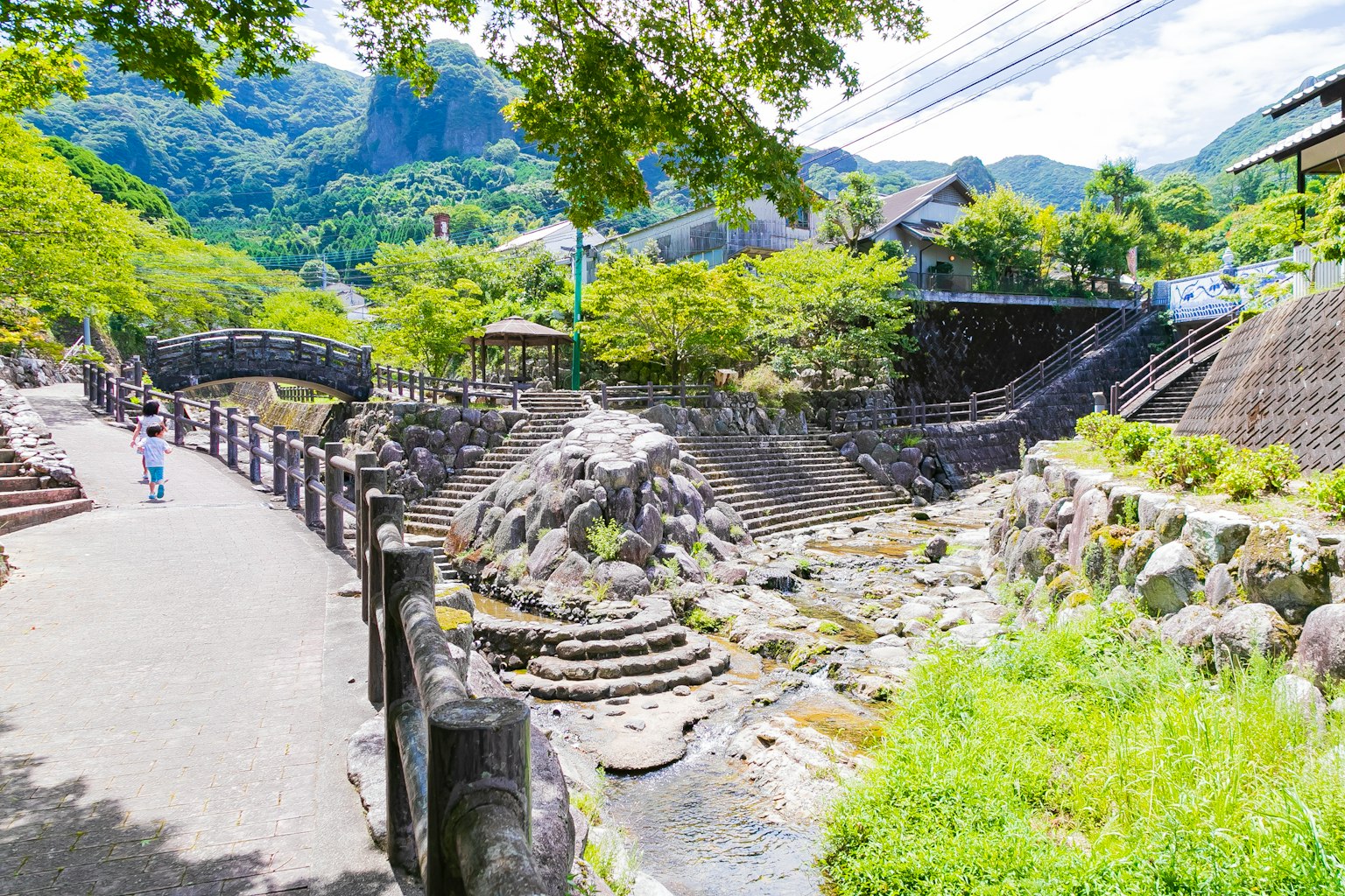 風景如畫的公園景觀，背景是流動的河流和郁郁蔥蔥的綠樹