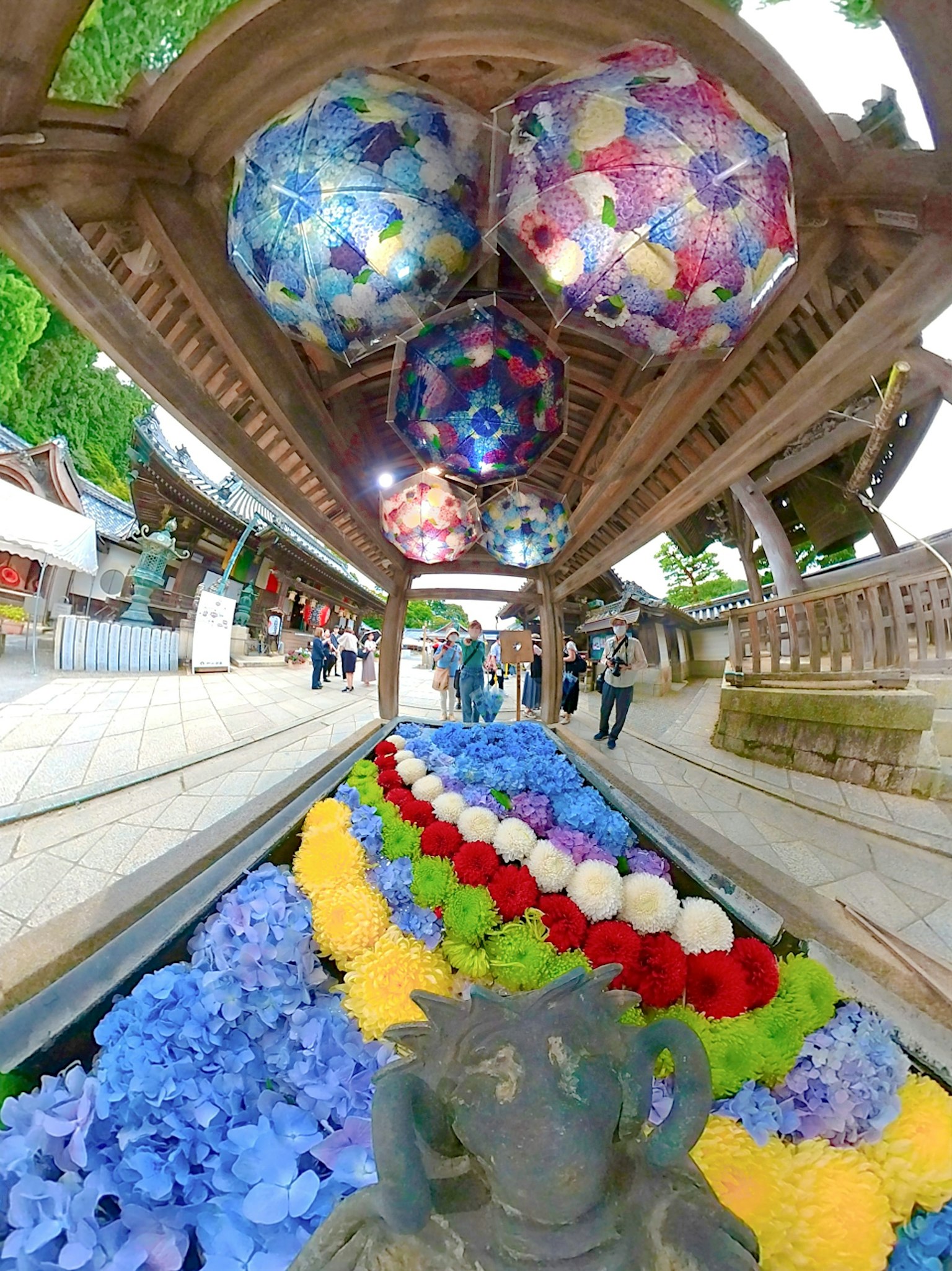 Fiori colorati lungo un sentiero di un santuario con ombrelli decorati sopra