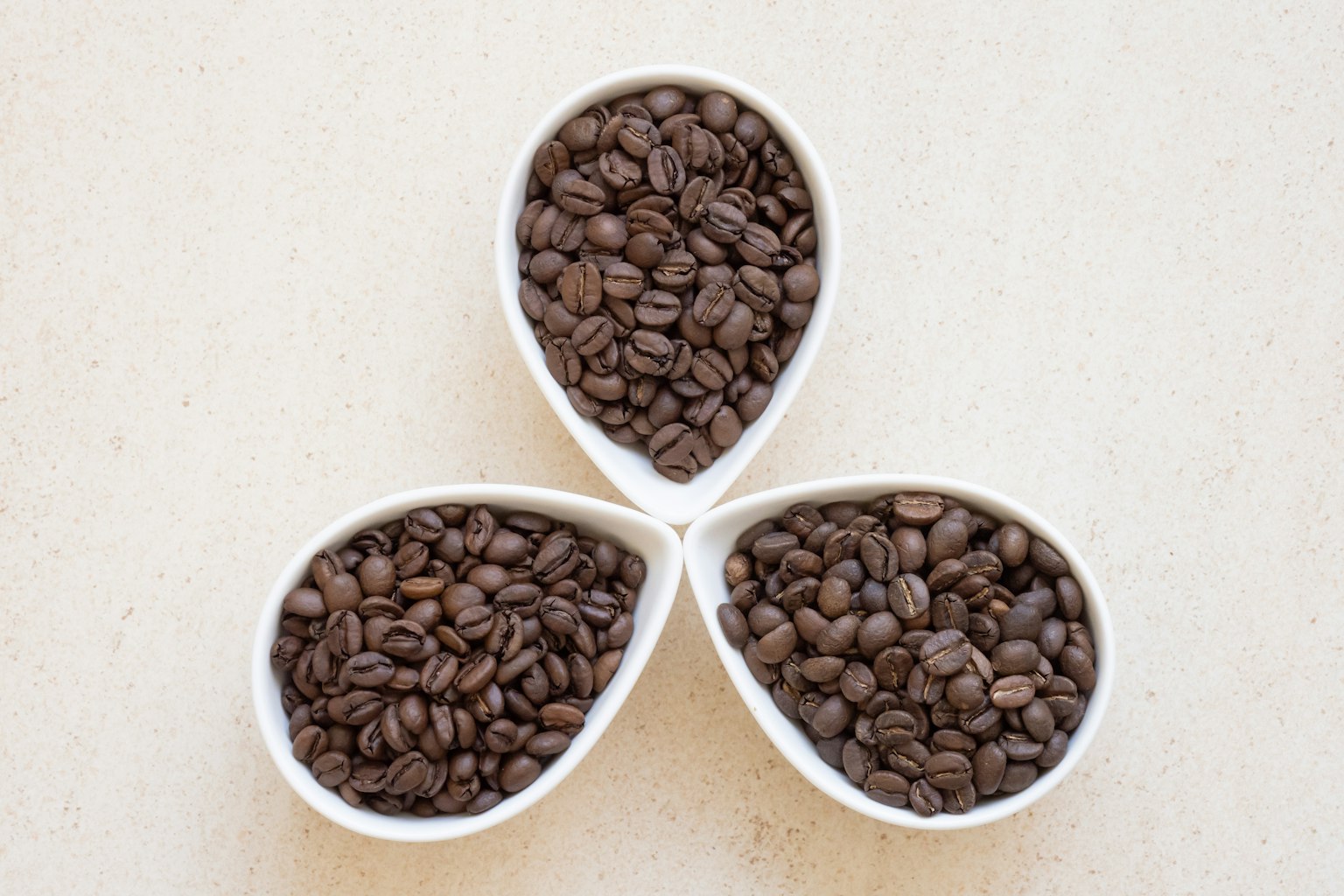 Tre piatti bianchi pieni di chicchi di caffè