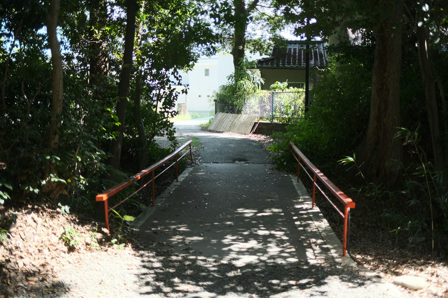 Entrance to a pathway surrounded by greenery featuring red railings