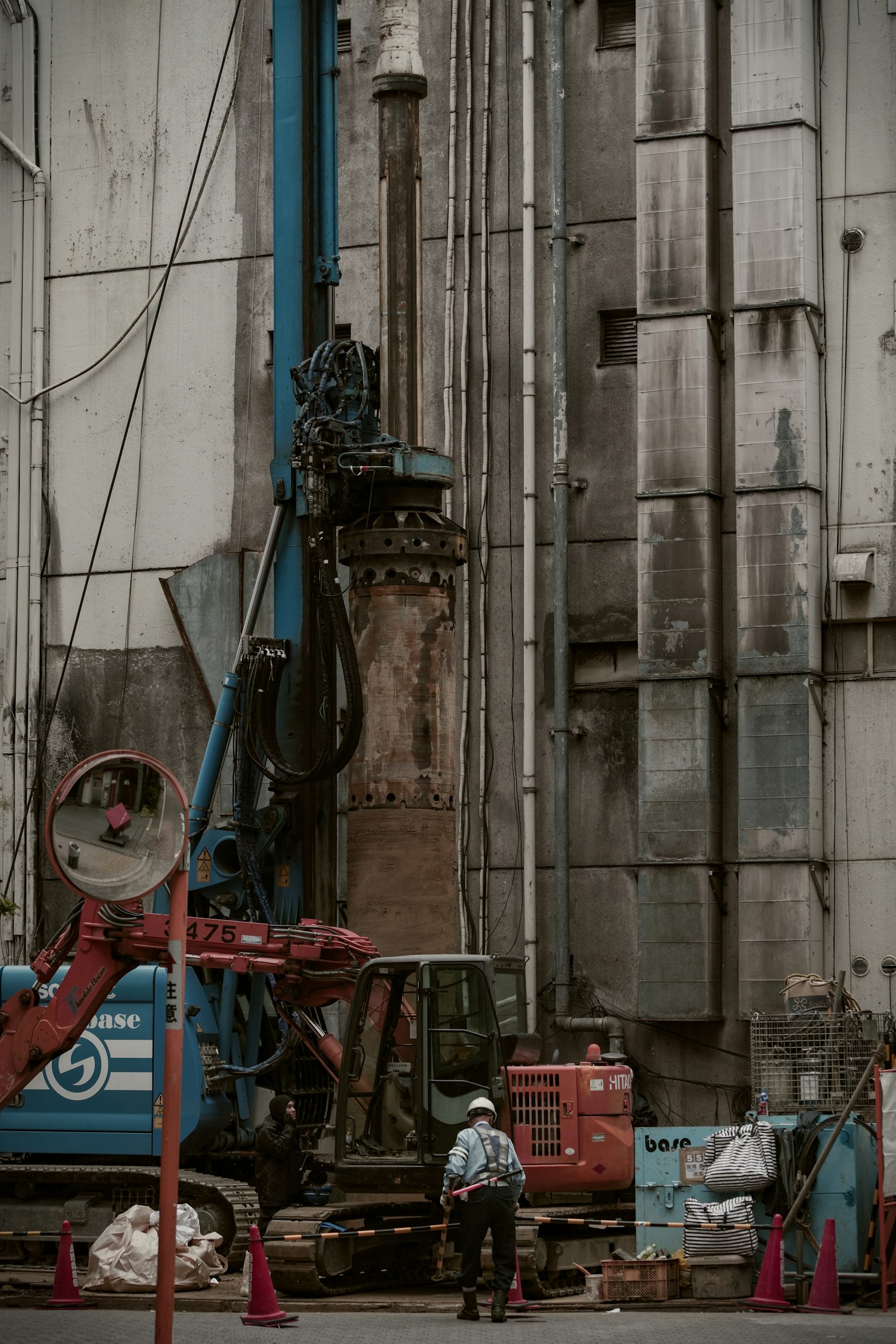 Sitio de construcción con una máquina de perforación y un trabajador en un entorno urbano