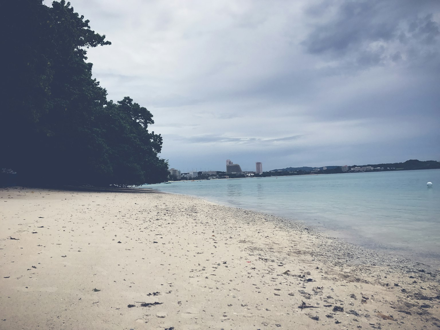 Ruhige Strandszene mit ruhigem Wasser und bewölktem Himmel