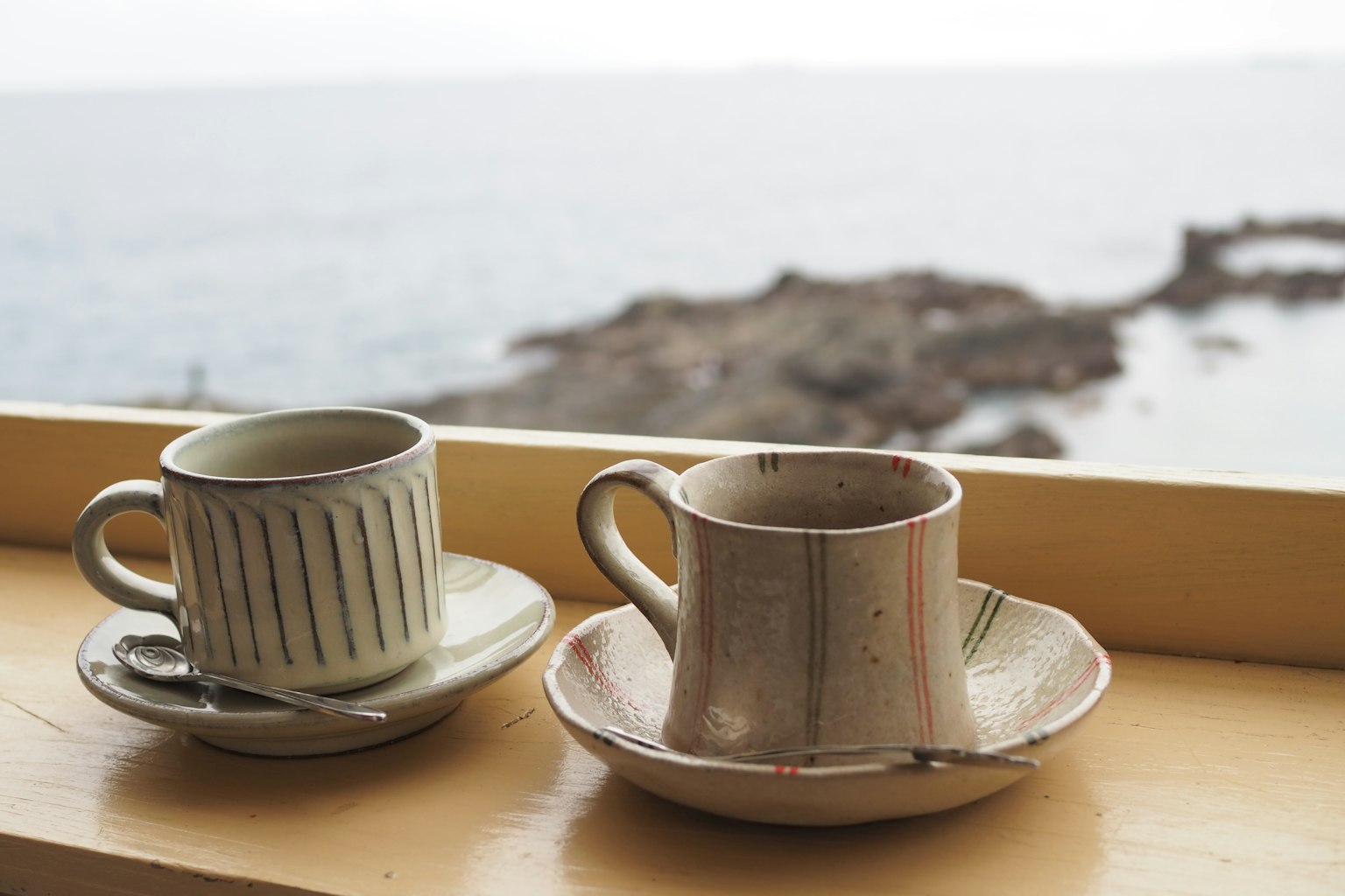 Deux tasses en céramique et sous-tasses avec vue sur l'océan en arrière-plan