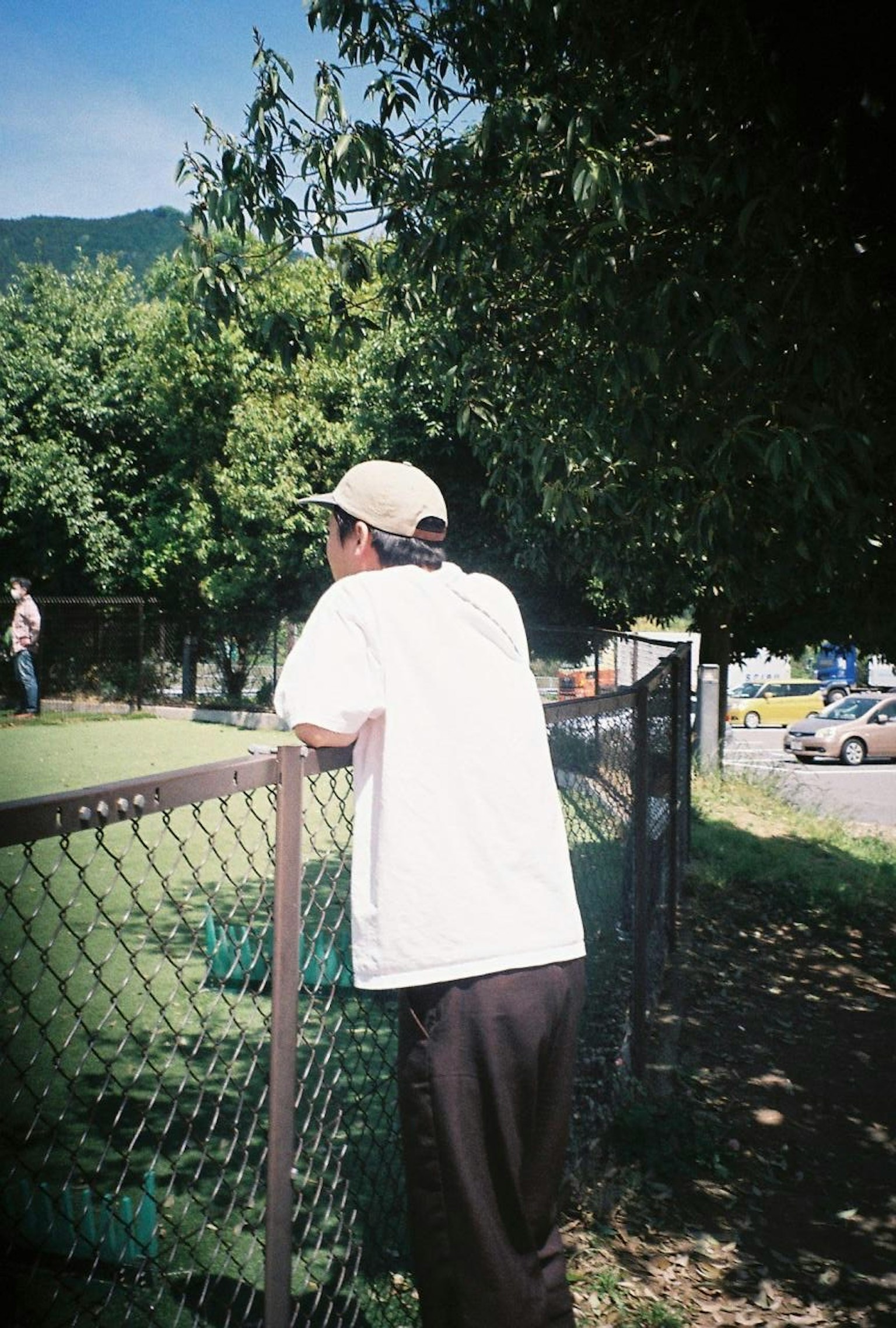 Man leaning on a fence in a park setting