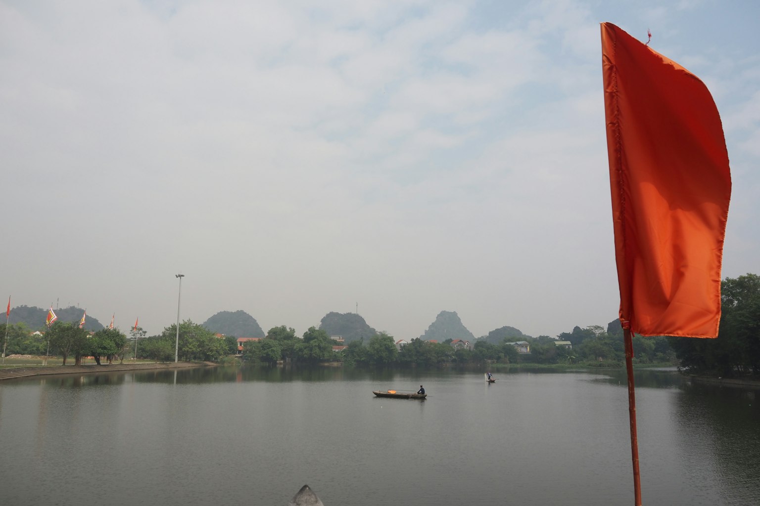 Malerscher Blick auf einen See mit einer roten Flagge und einem Boot auf dem Wasser umgeben von Bergen