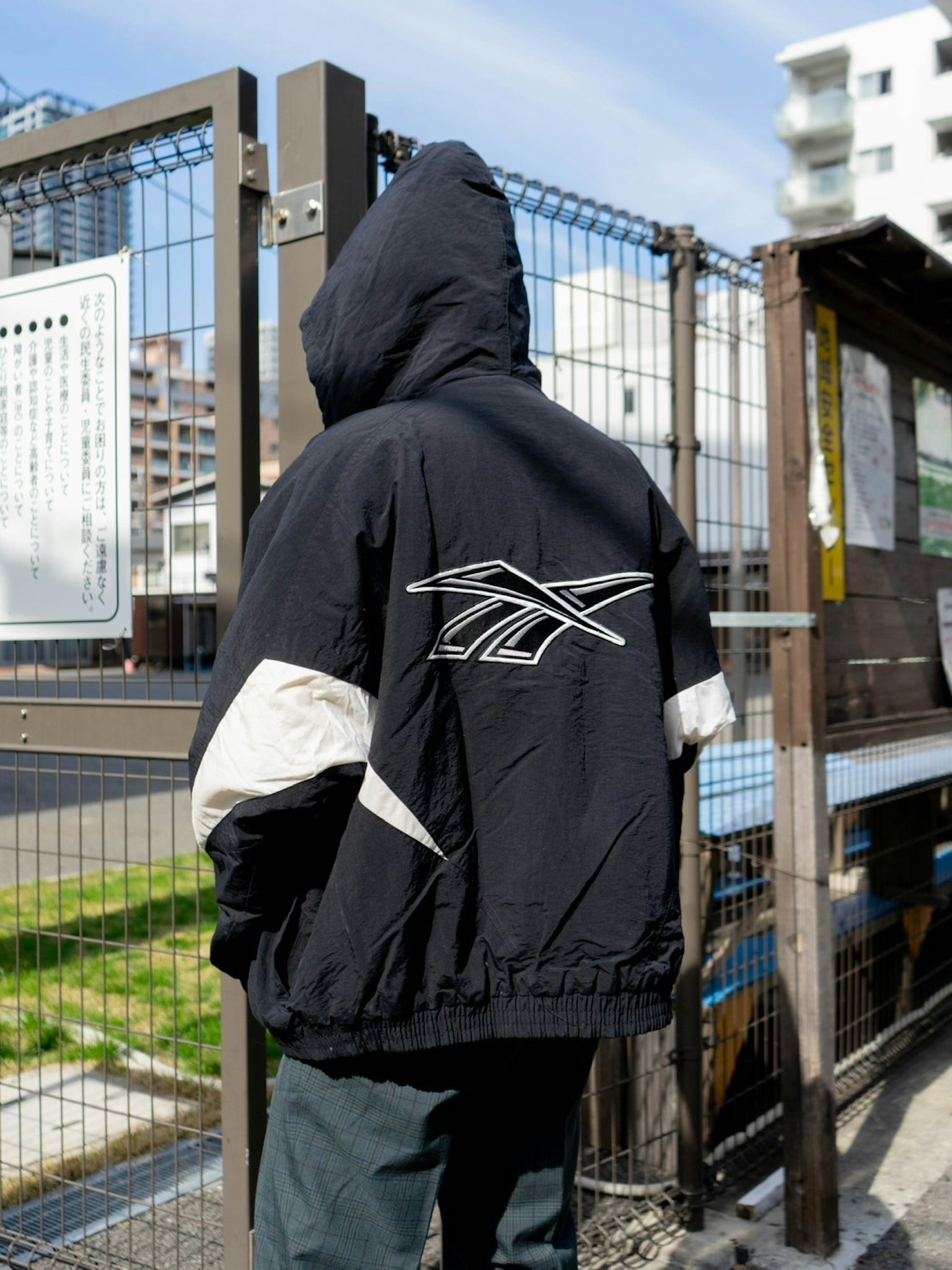 Person wearing a black jacket with a hood standing with back to the camera