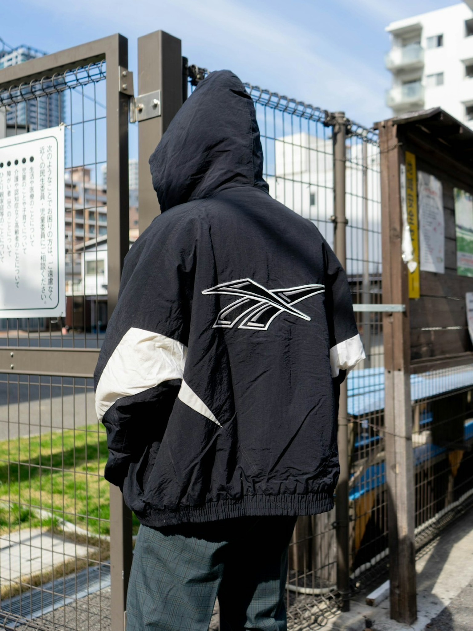 Person mit schwarzer Kapuzenjacke, Rücken zur Kamera