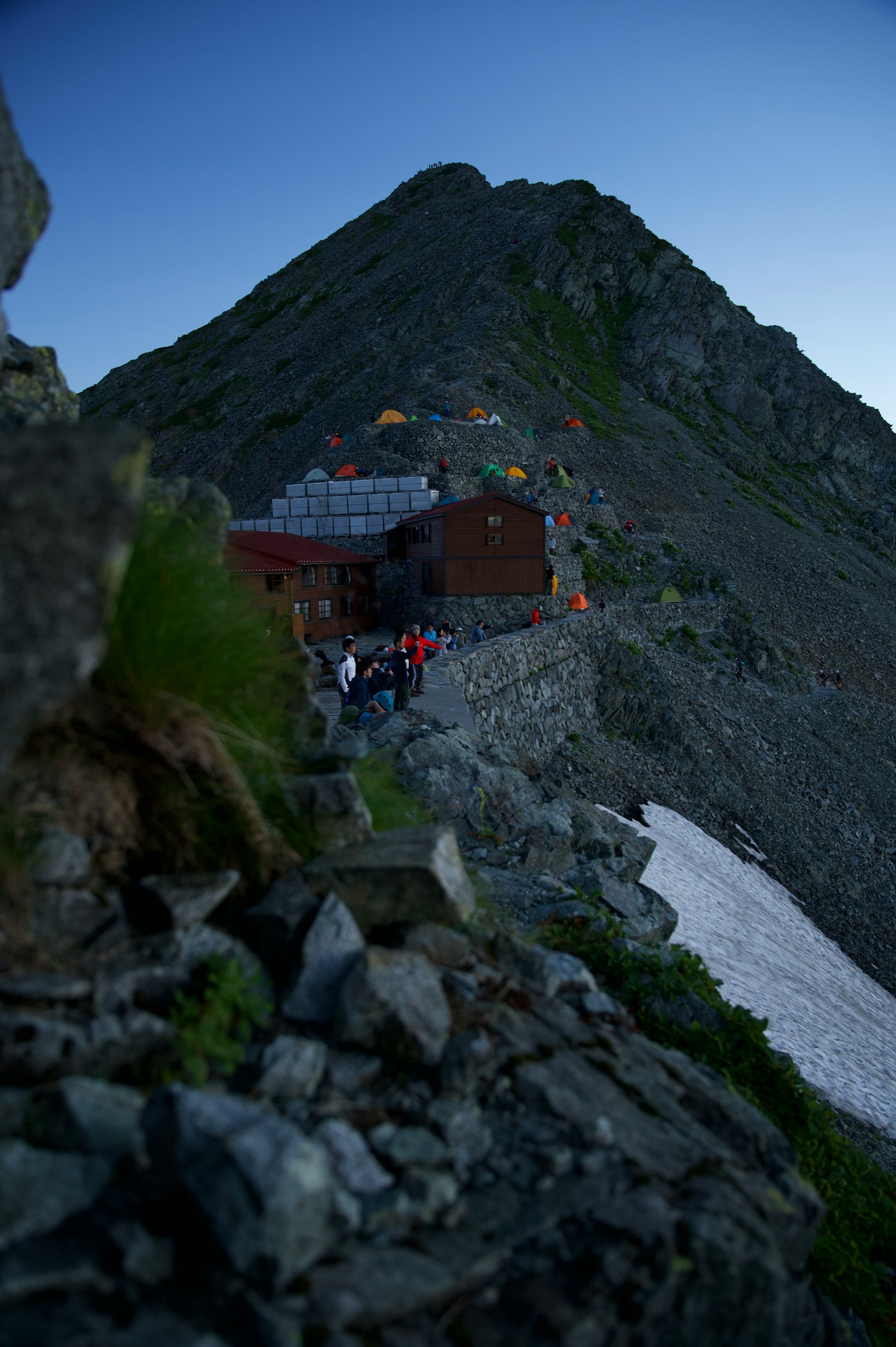Un chalet de montagne sur une pente avec des randonneurs visibles