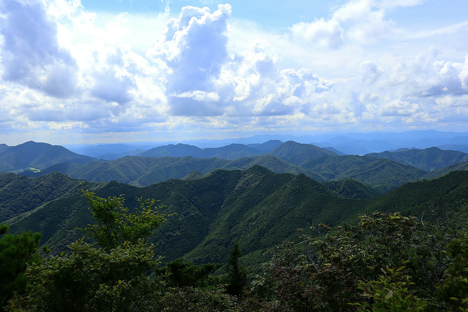 Paysage de montagne avec des collines vertes sous un ciel bleu et des nuages blancs