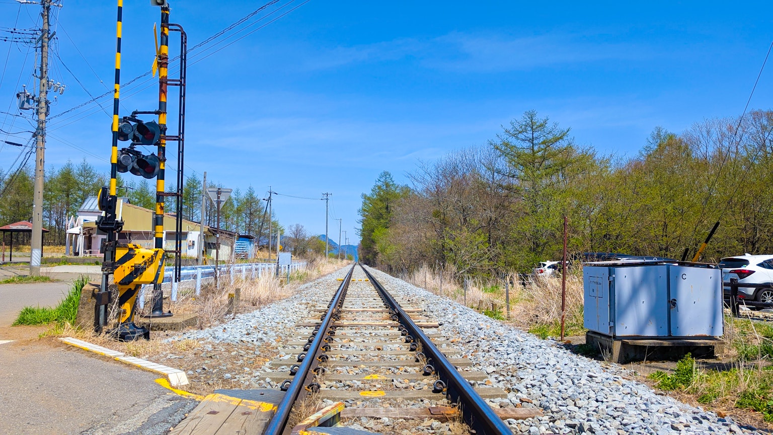 รางรถไฟใต้ท้องฟ้าสีฟ้าสดใสพร้อมสัญญาณและพืชพรรณรอบข้าง