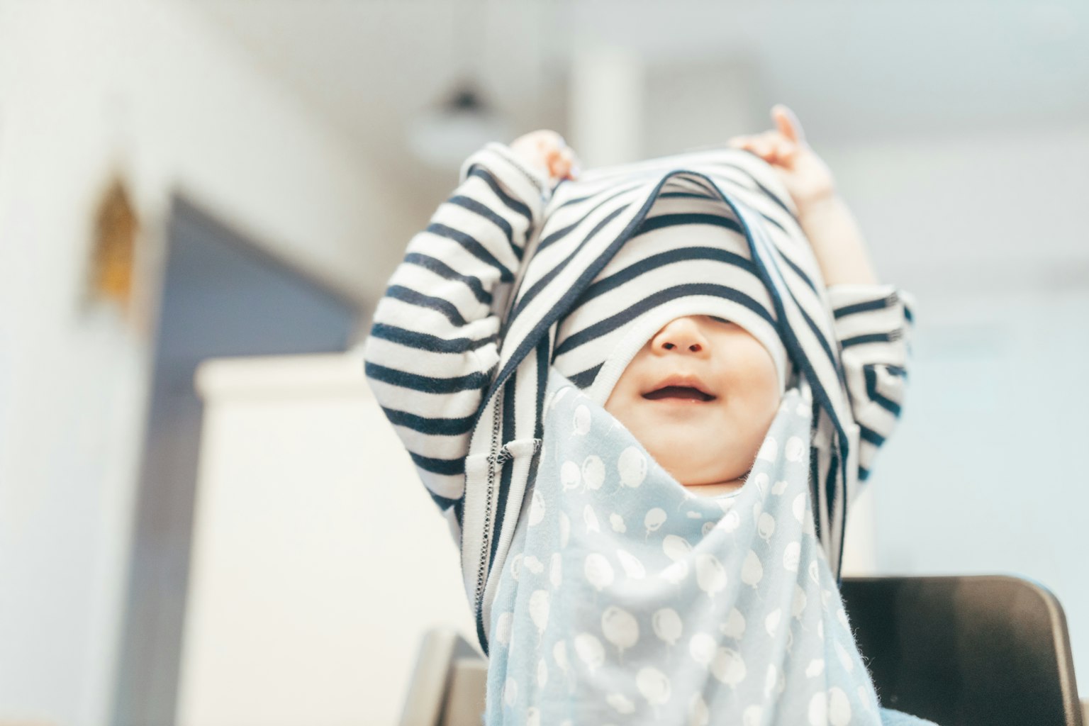 Baby spielt mit einem gestreiften Hut und lächelt