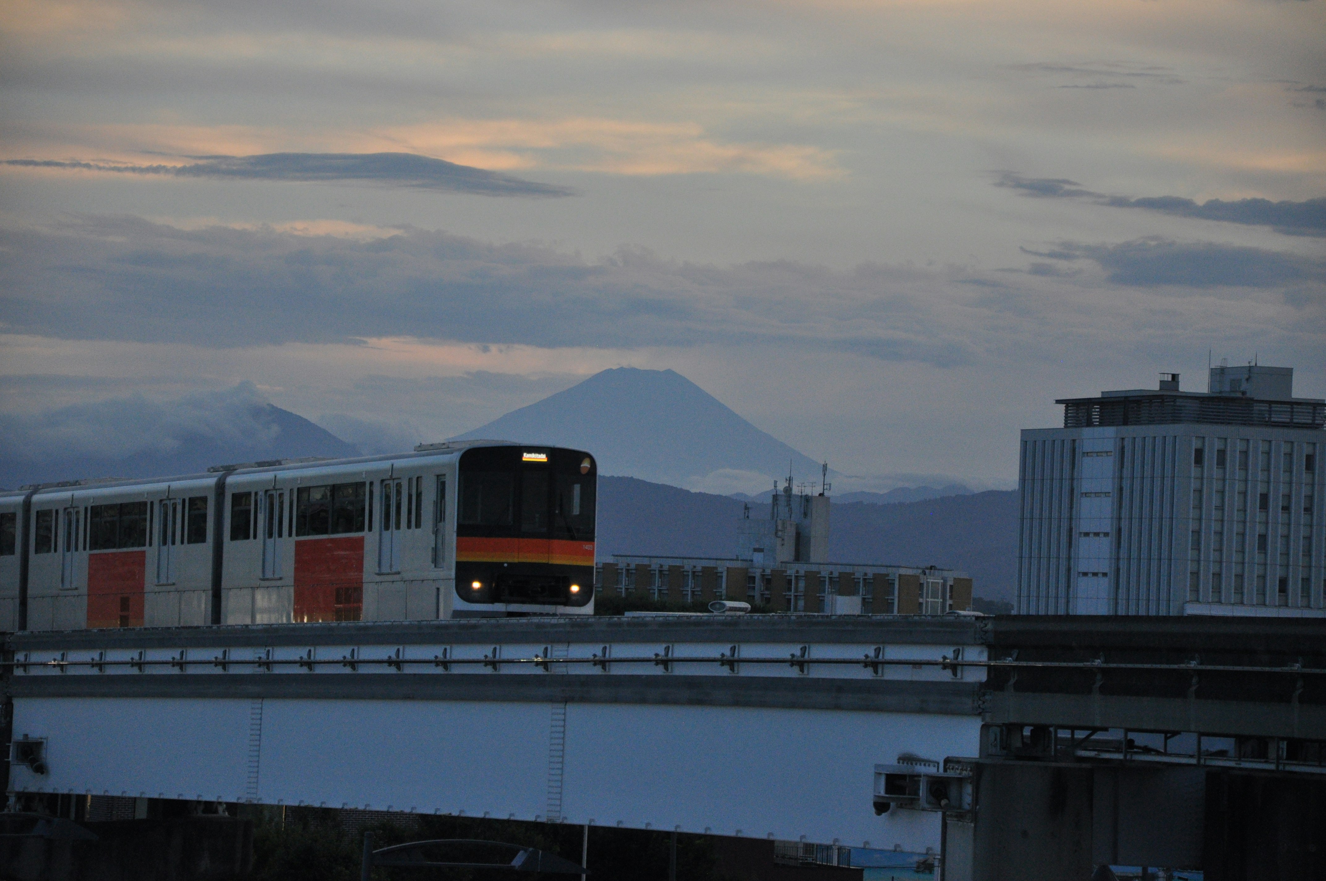 夕暮れの高架を走る列車と遠くの山並み
