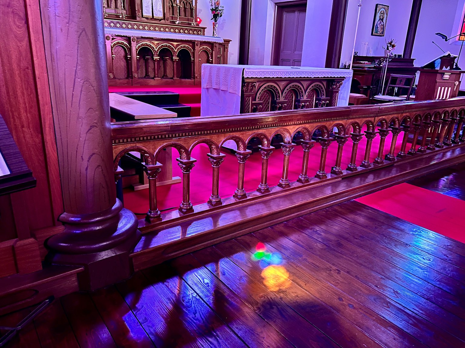 Interior de una iglesia con una barandilla de madera y una alfombra roja