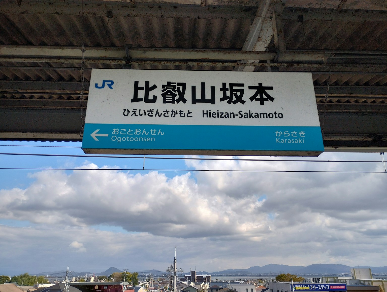 Schild der Station Heizan-Sakamoto mit blauem Himmel und Wolken im Hintergrund