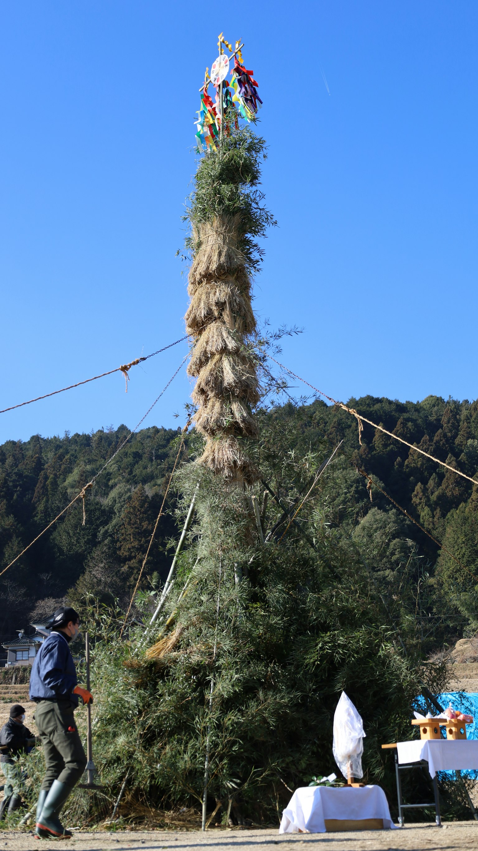 Alta torre de bambú decorada para un festival con personas alrededor