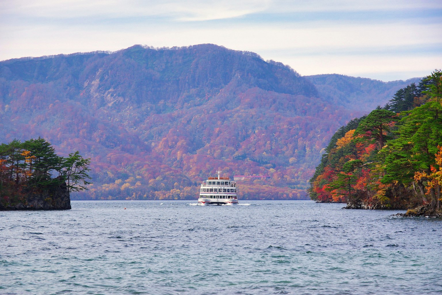 Touristenboot, das auf einem See mit herbstlichem Laub navigiert