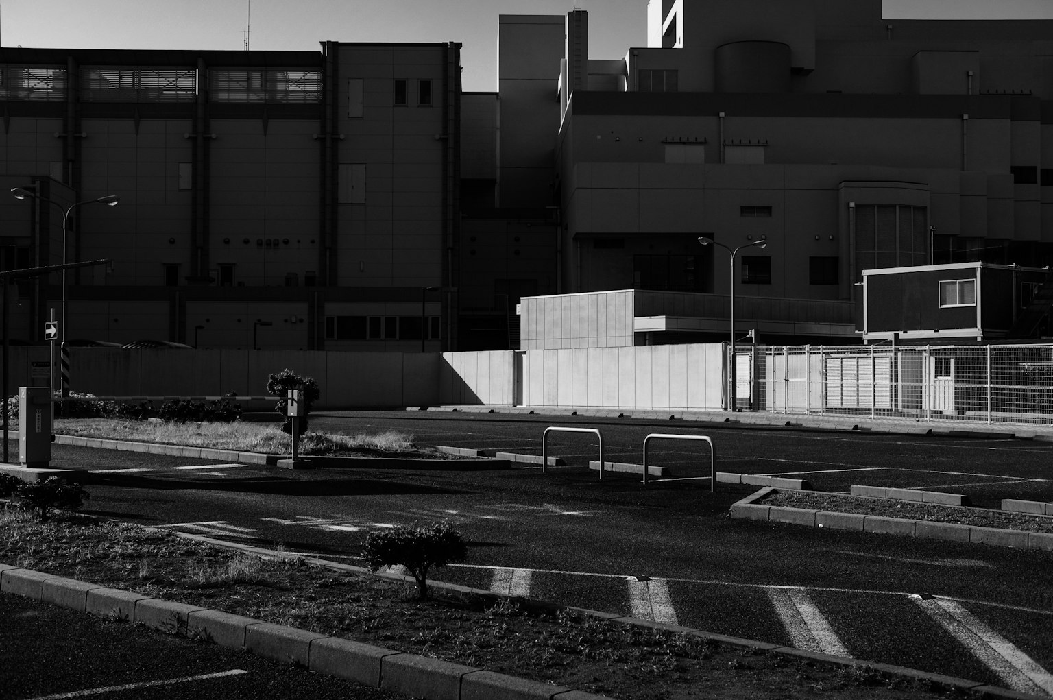 Vista in bianco e nero di un parcheggio con edifici industriali sullo sfondo
