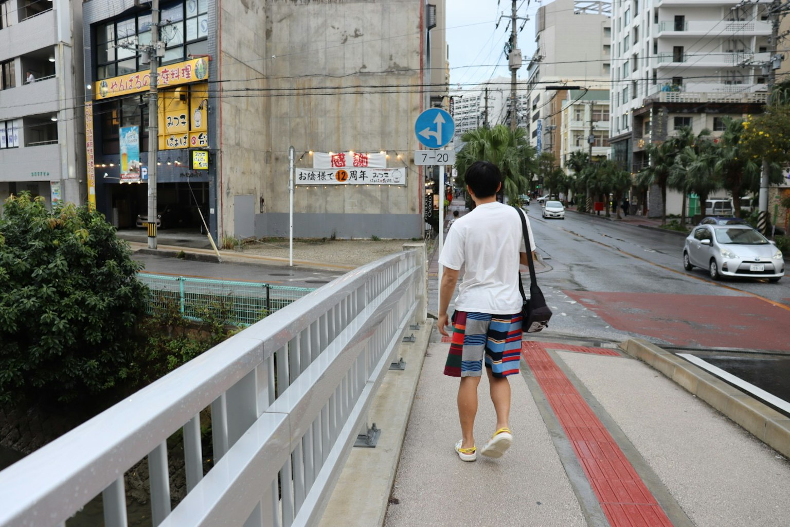 男子走在行人桥上，背景是建筑和街道