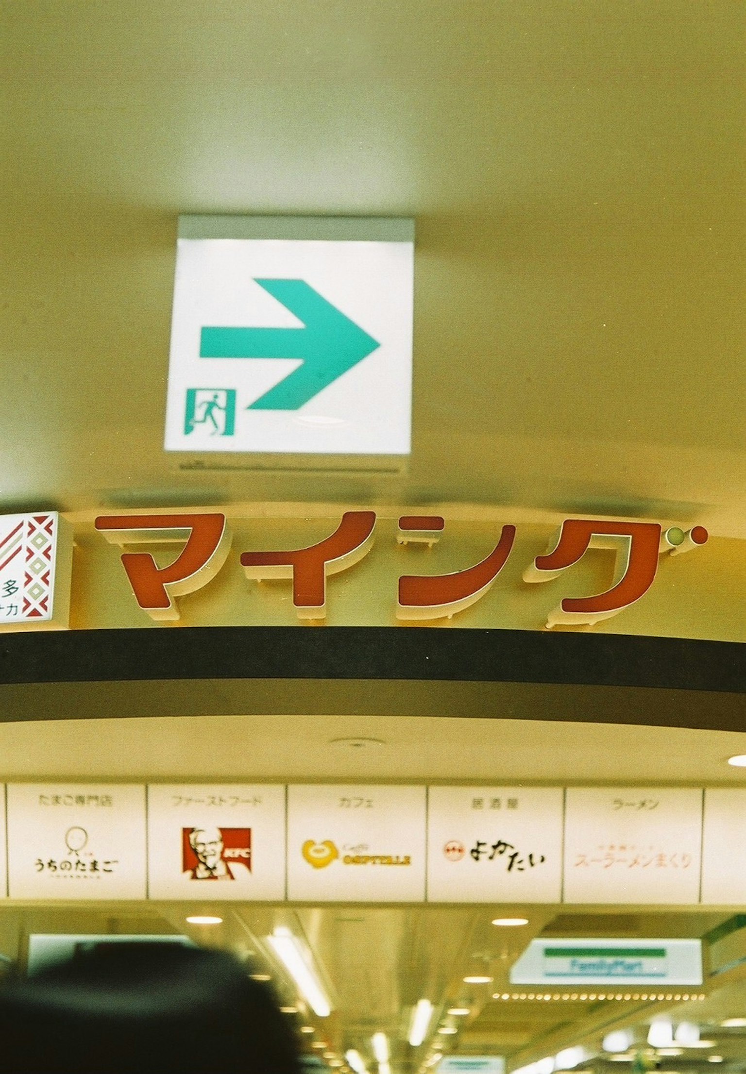 Interior de un espacio comercial con un letrero verde y el letrero "マイシング"