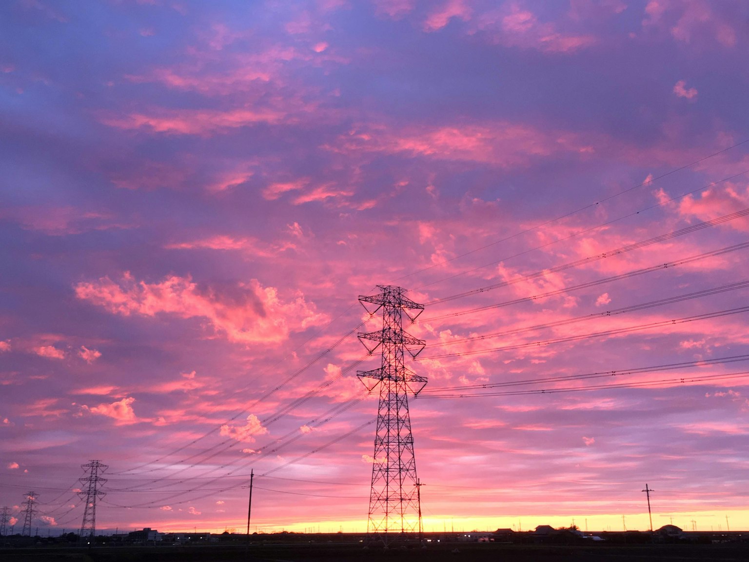Coucher de soleil violet vibrant avec des lignes électriques en silhouette