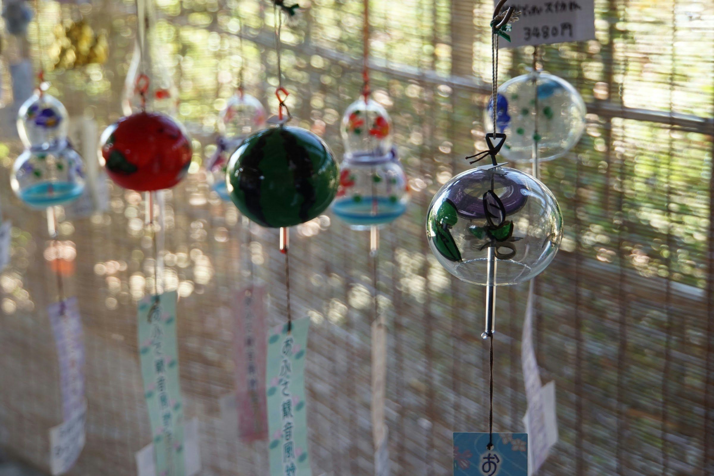 clochettes éoliennes colorées suspendues à un store en bambou