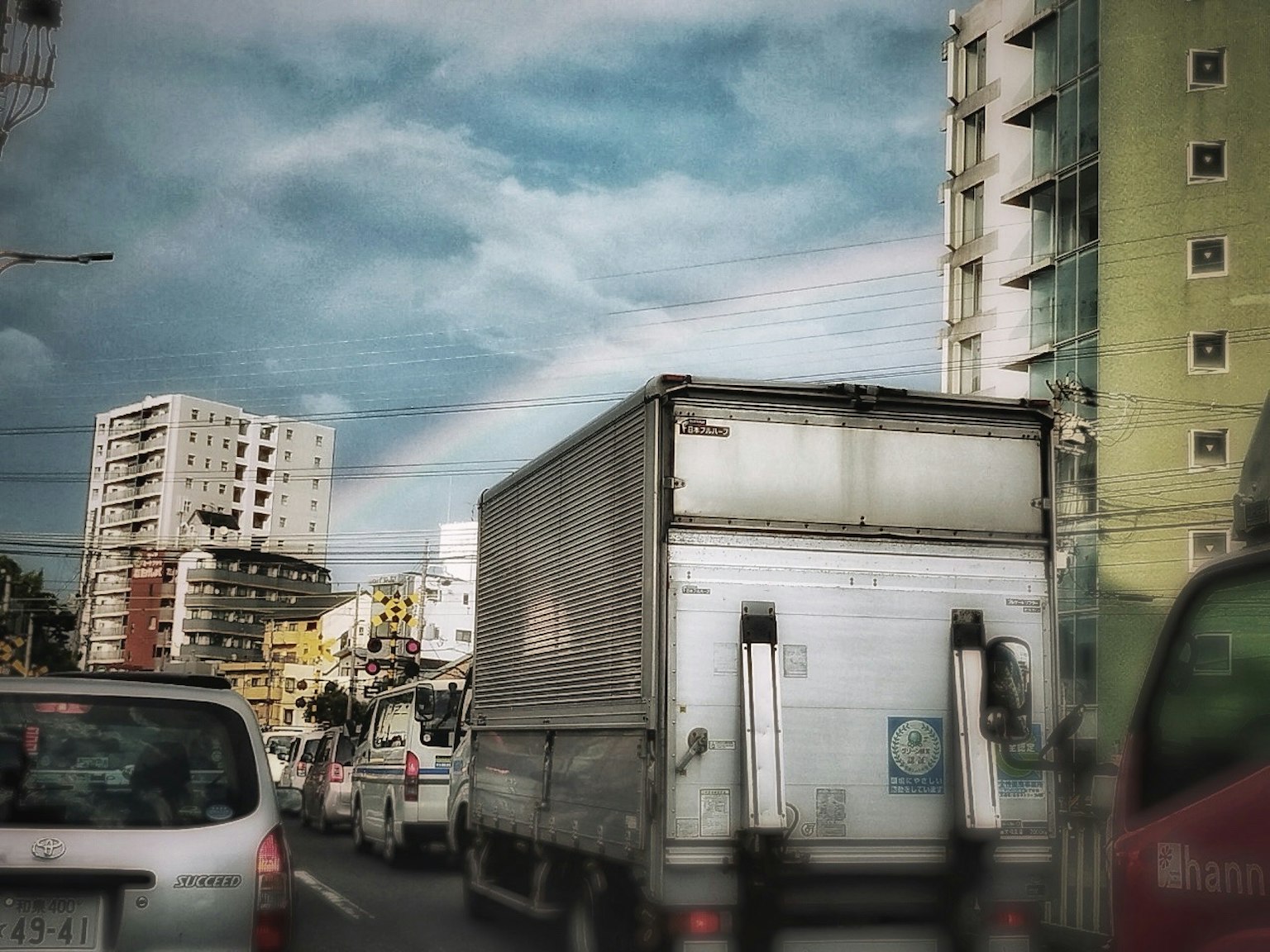 Camion nel traffico urbano con un arcobaleno sullo sfondo