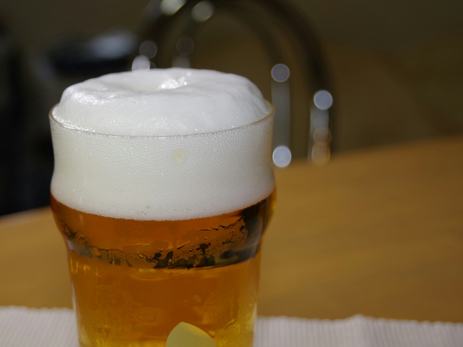Un bicchiere di birra con una schiuma spessa posato su un tavolo di legno