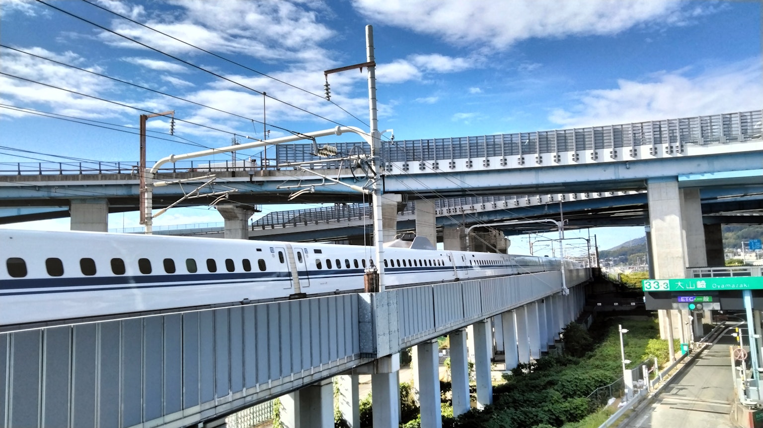 Cảnh giao nhau giữa Shinkansen và cầu cao với bầu trời xanh và mây