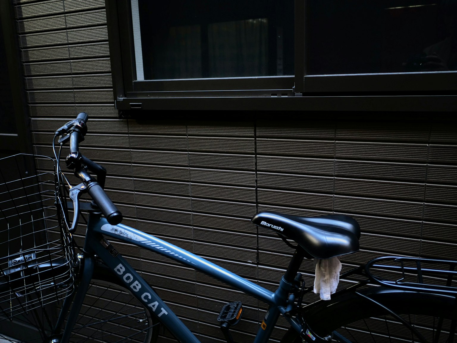 Una bicicletta blu parcheggiata accanto a un muro marrone in un ambiente tranquillo