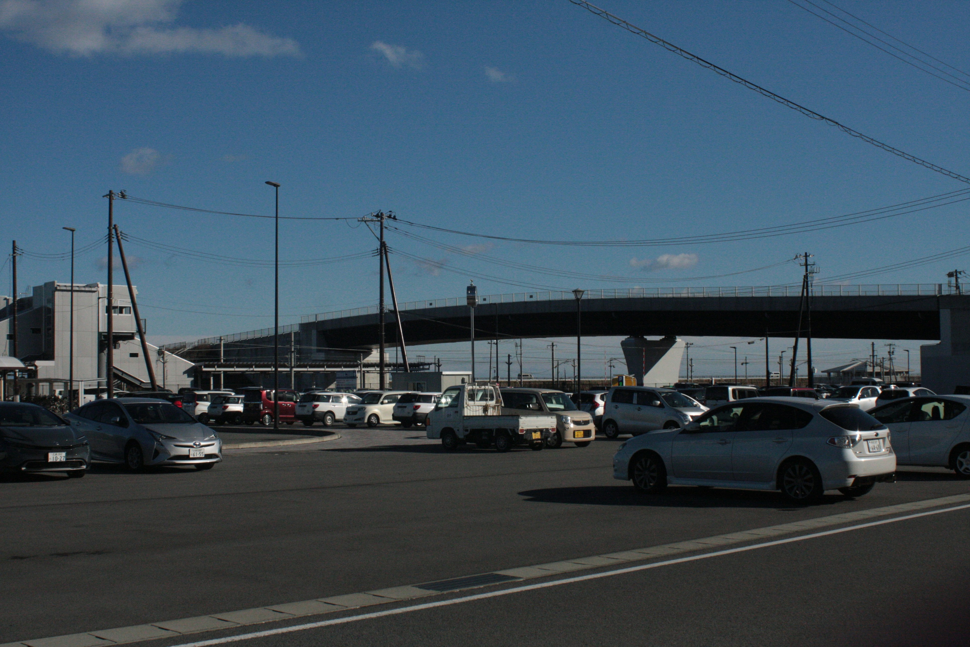 road scene with a parking lot and elevated structure under a blue sky