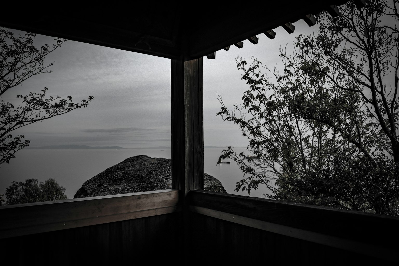 Vue d'une mer calme et d'arbres depuis une structure en bois