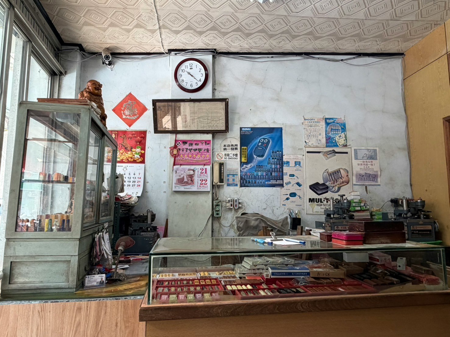 古い店内のカウンターとガラスケースがあり 壁にはポスターやカレンダーが貼られている 時計が掛かっている