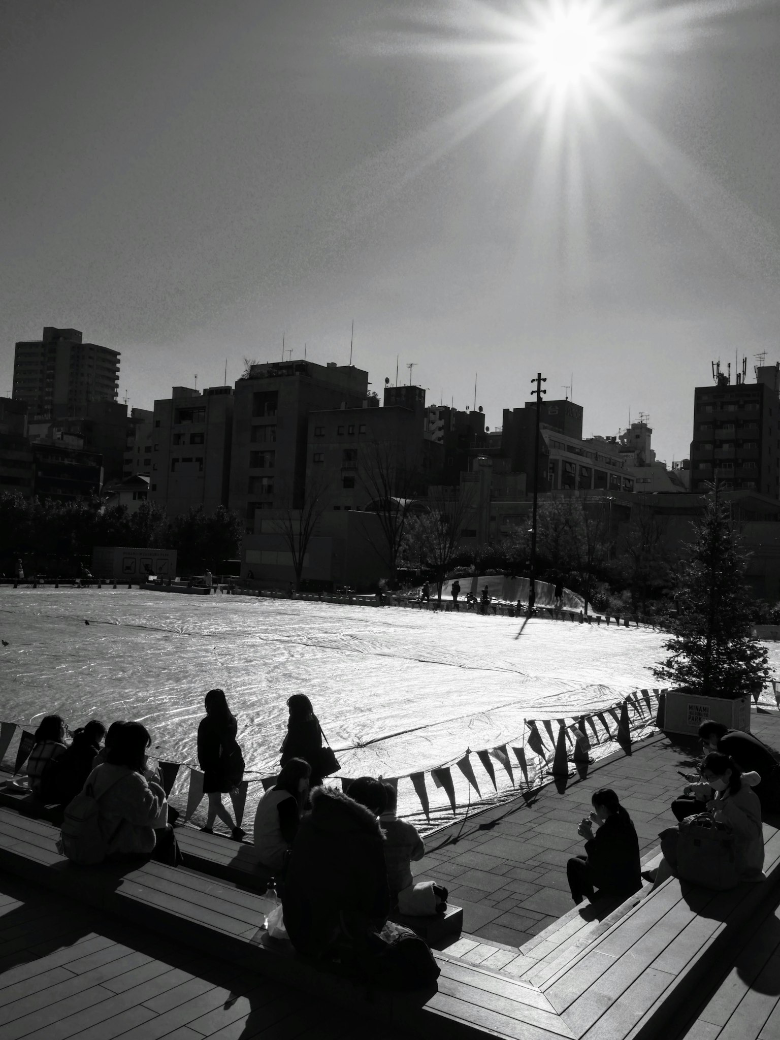 Urban scene with strong sunlight and people sitting