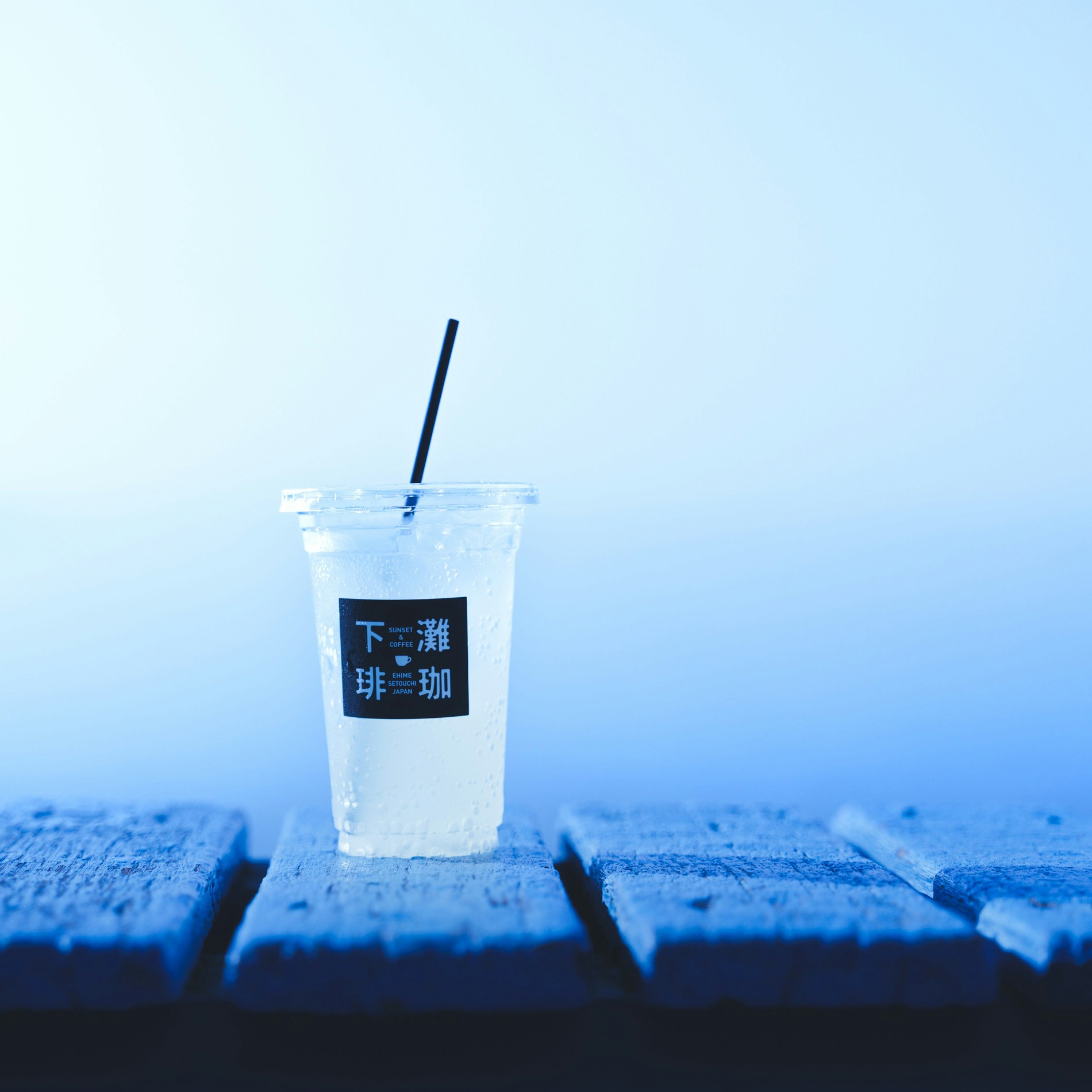 海辺のテーブルに置かれた氷入りソーダドリンクのグラス「下に羅珈」