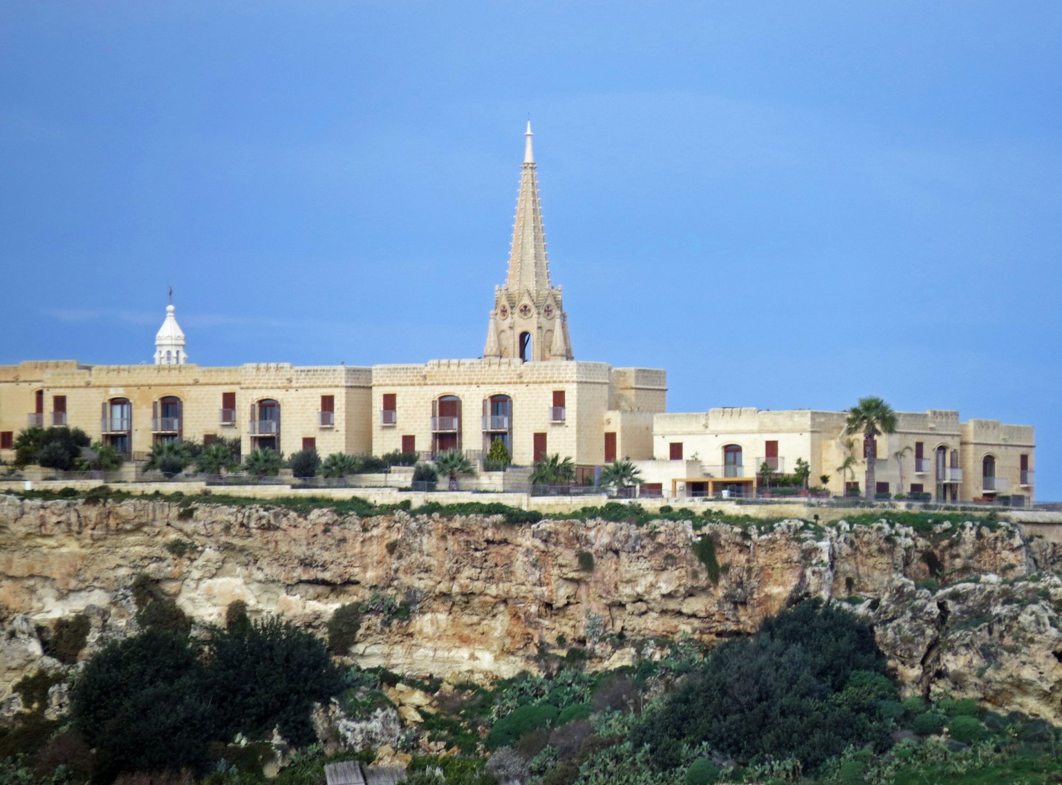 Historic building and spire on a cliff under a blue sky