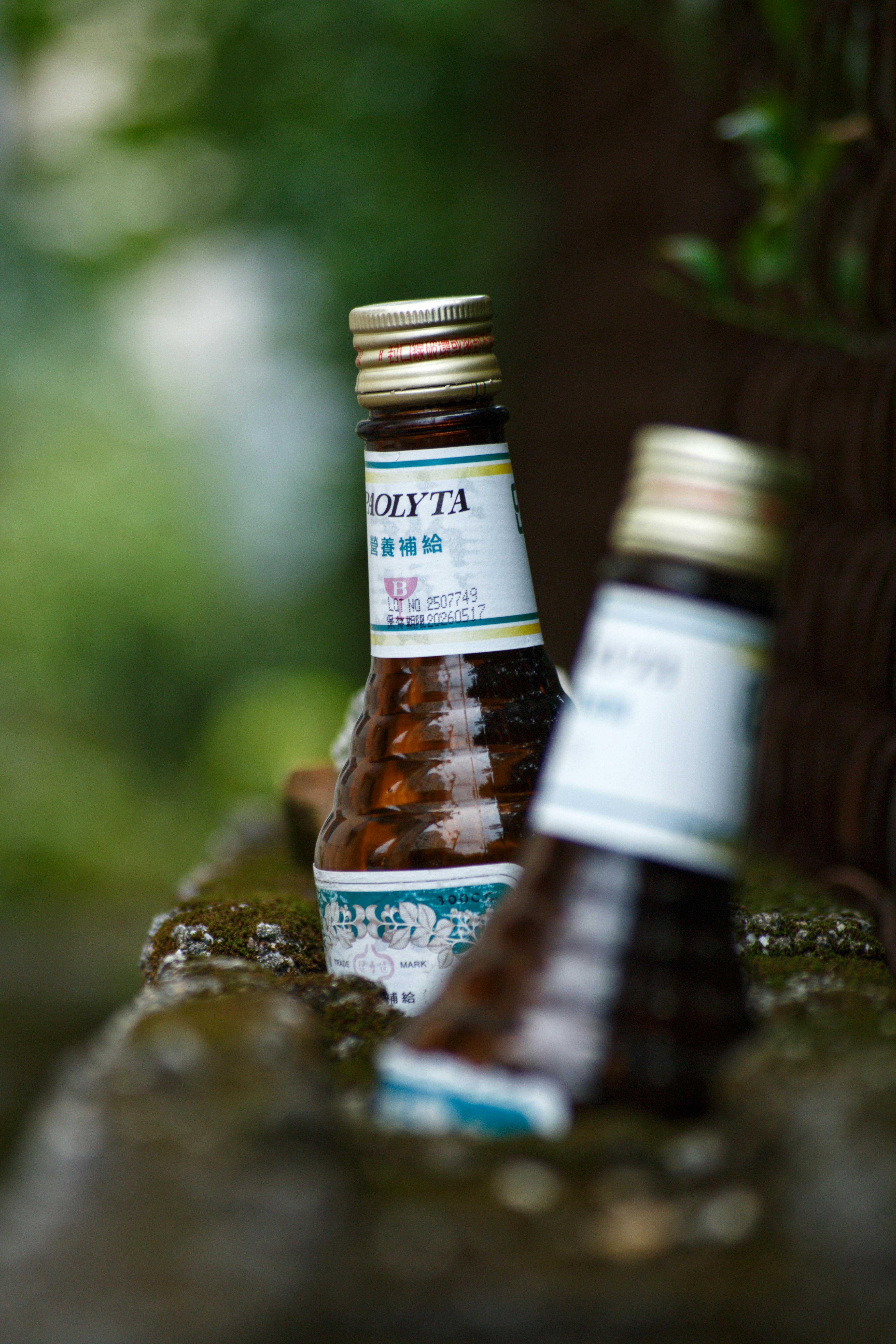 緑の背景にある二本の瓶入り飲料のボトル ボトルは茶色でラベルが白と青