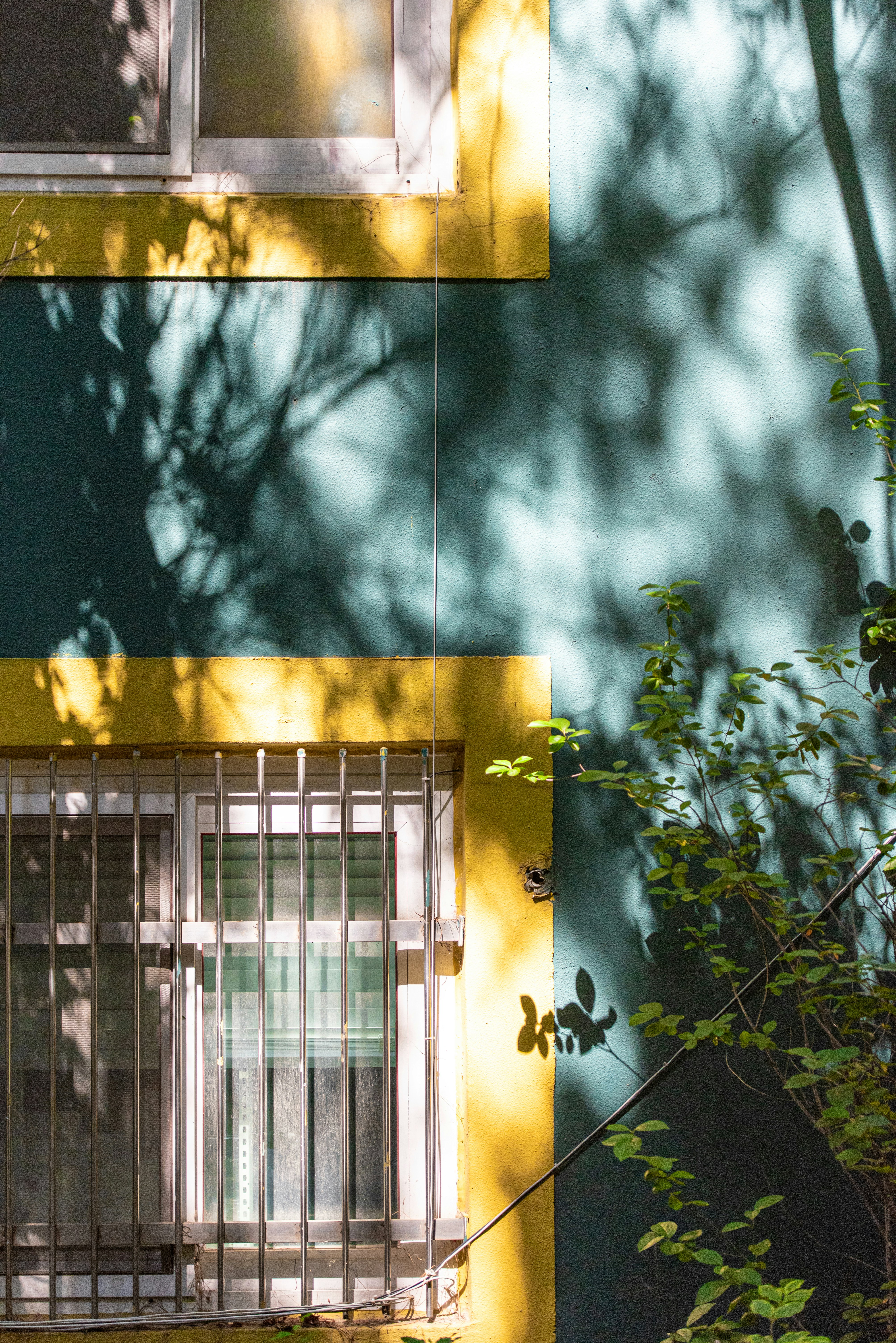 facciata di un edificio al sole con inferriate alla finestra e ombre a chiazze