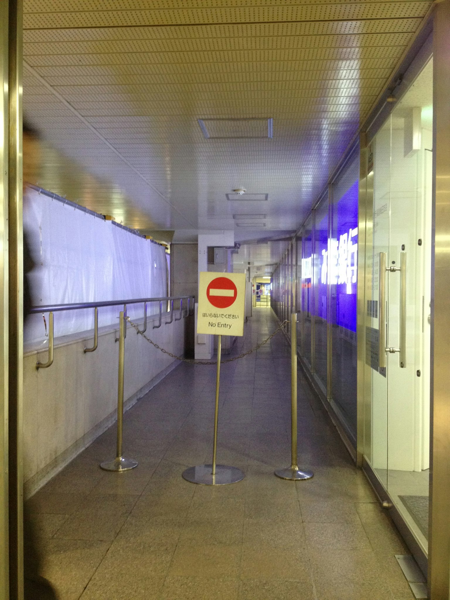 Largo corredor con un cartel de no entrada rojo y paredes de vidrio
