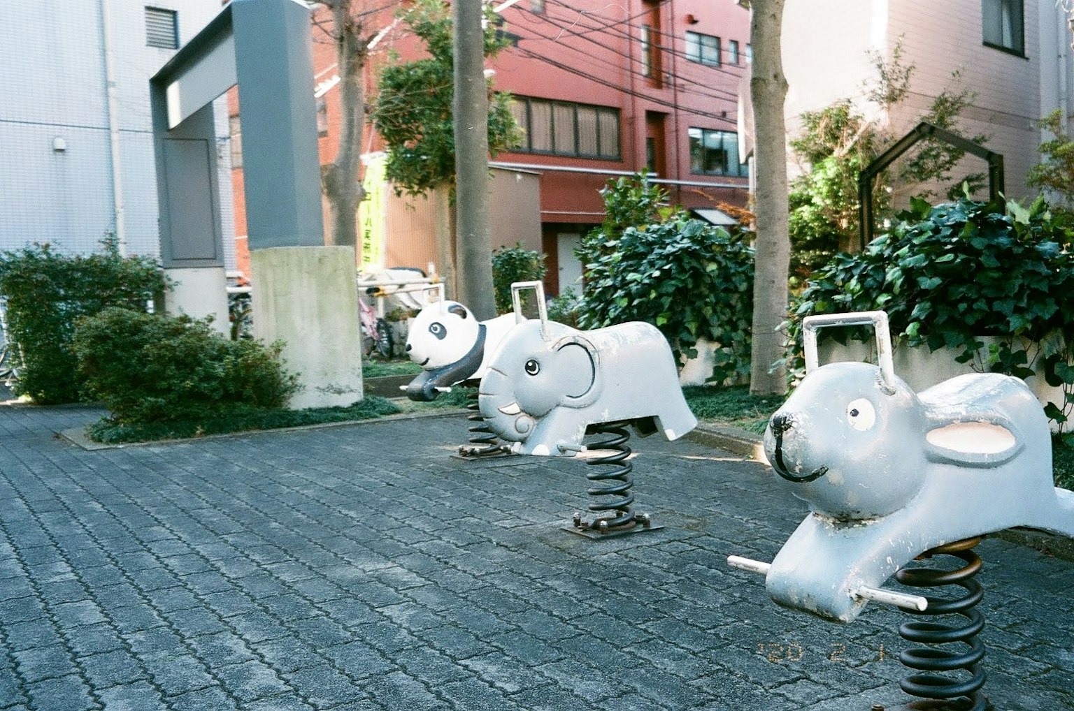 แถวของของเล่นสปริงสีขาวรูปแกะในสนามเด็กเล่น