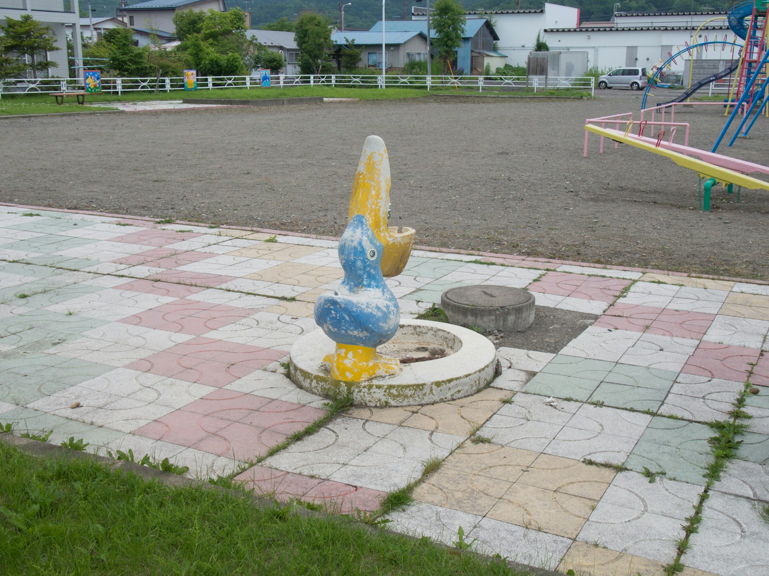 Colorful drinking fountain statue near playground equipment