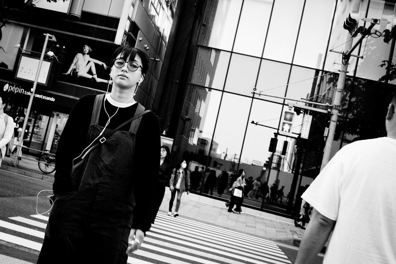 Man standing at a crosswalk with glass buildings in the background
