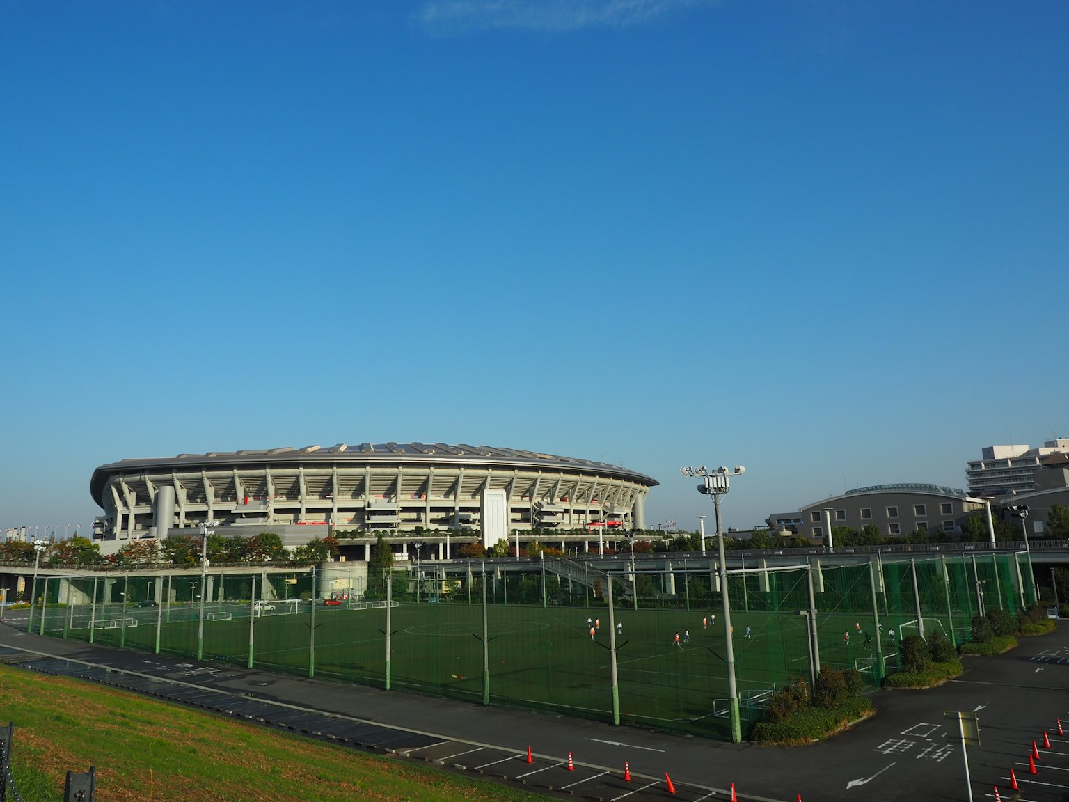 Pemandangan lapangan sepak bola dan stadion di bawah langit biru yang cerah