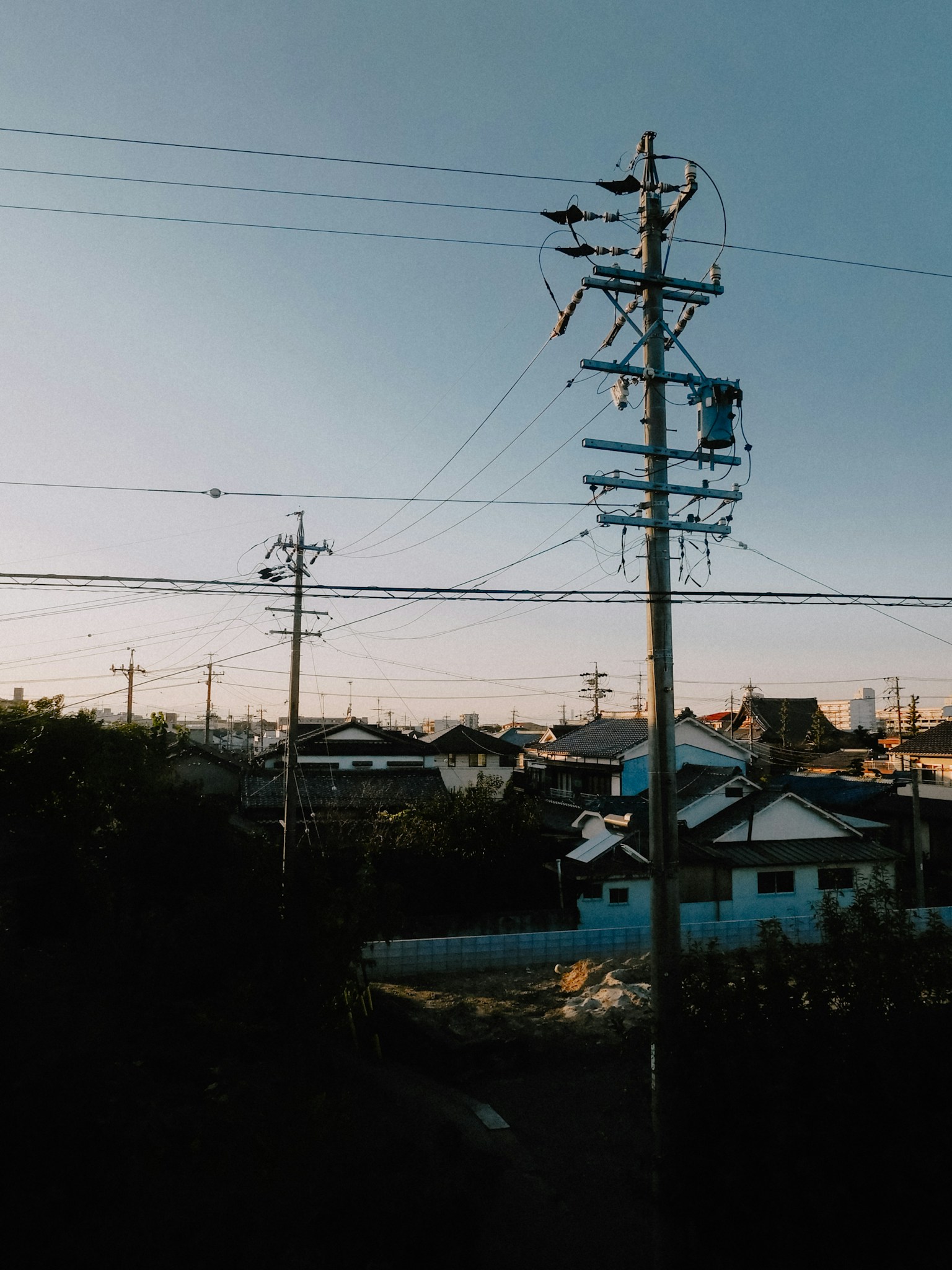 Linee elettriche e case al tramonto con cielo blu chiaro
