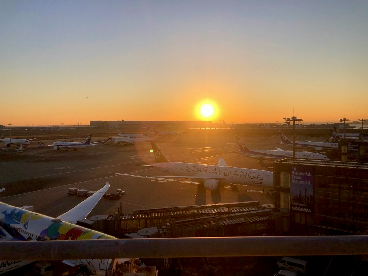 Schöne Sonnenuntergangsansicht am Flughafen mit Flugzeugen auf der Landebahn und einem hellen orangefarbenen Himmel