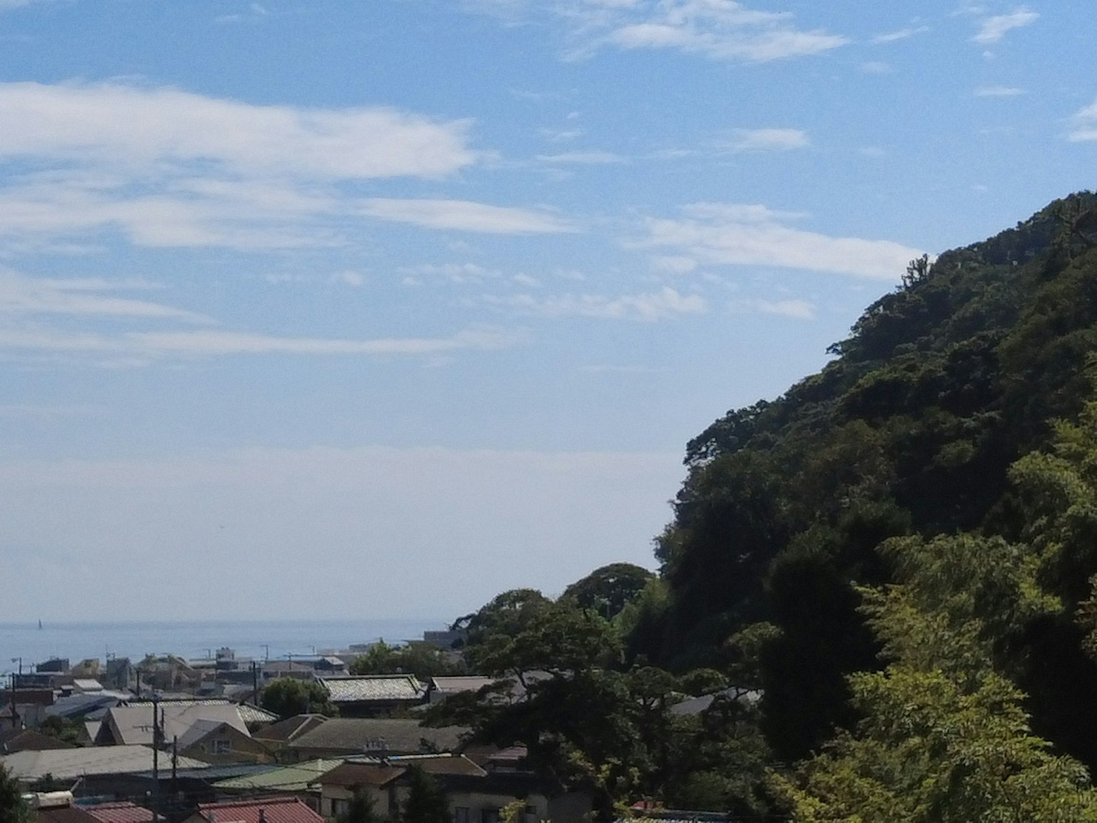 Landscape with blue sky and clouds featuring mountains and houses